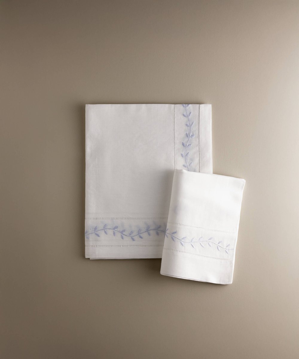 Sábana encimera de cuna con hojas bordadas en azul y funda de almohada